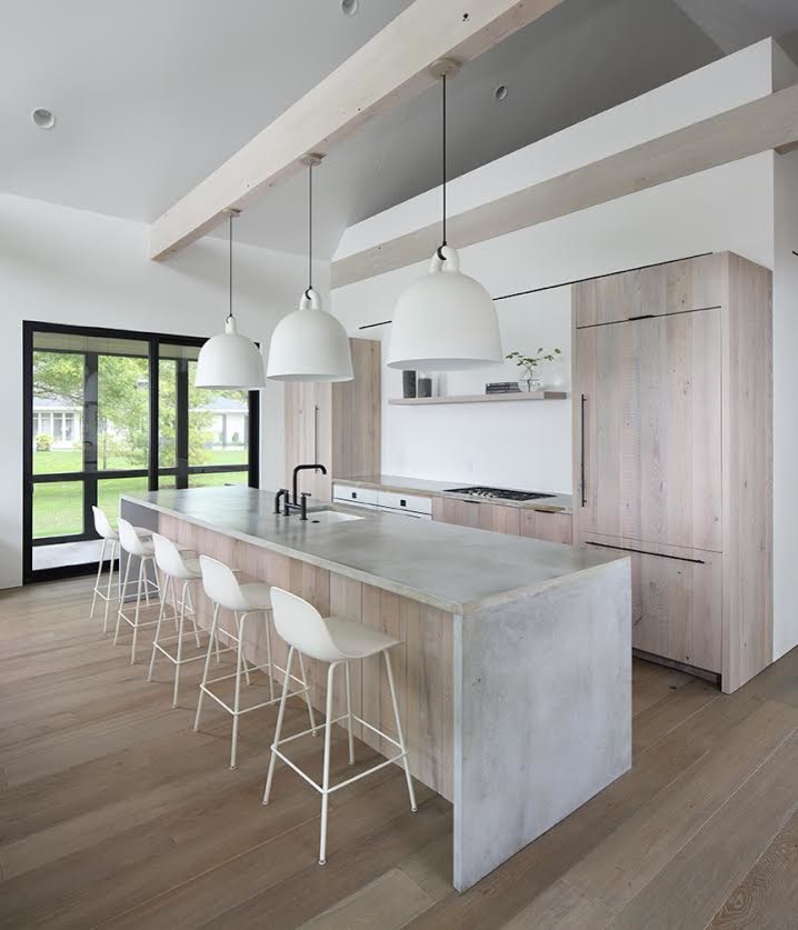 This is an example of a mid-sized modern single-wall open plan kitchen in Other with with island, an undermount sink, flat-panel cabinets, light wood cabinets, concrete benchtops, panelled appliances, medium hardwood floors, brown floor and grey benchtop.