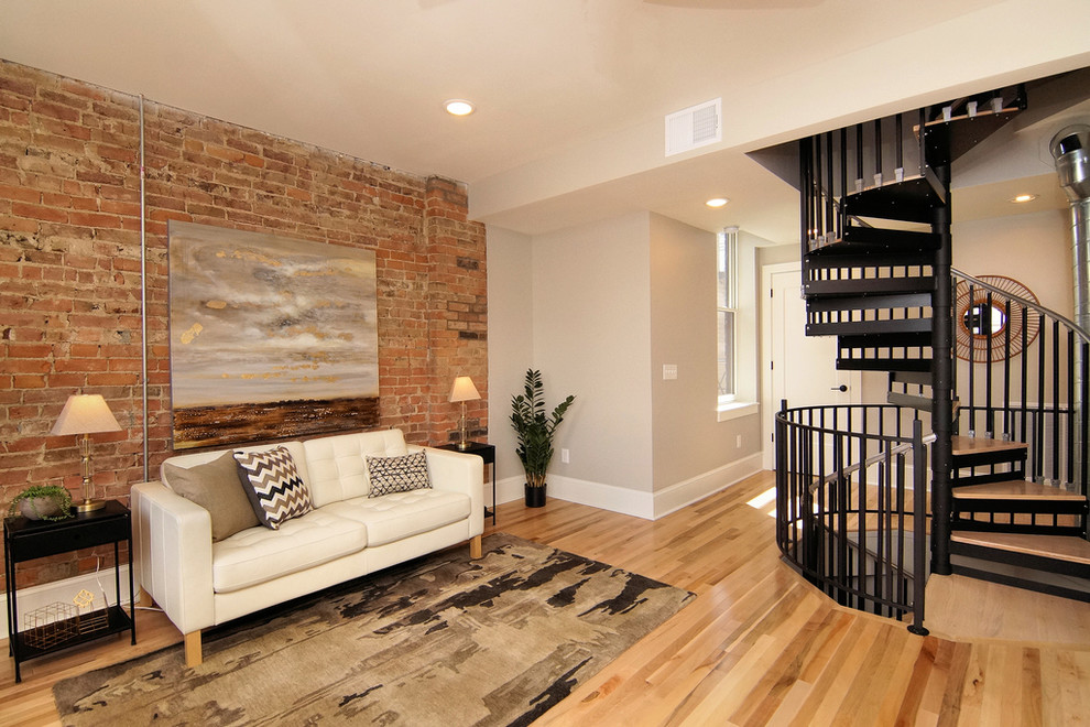 Photo of a large industrial open concept family room in Cincinnati with grey walls, light hardwood floors, a standard fireplace, a brick fireplace surround, no tv and beige floor.