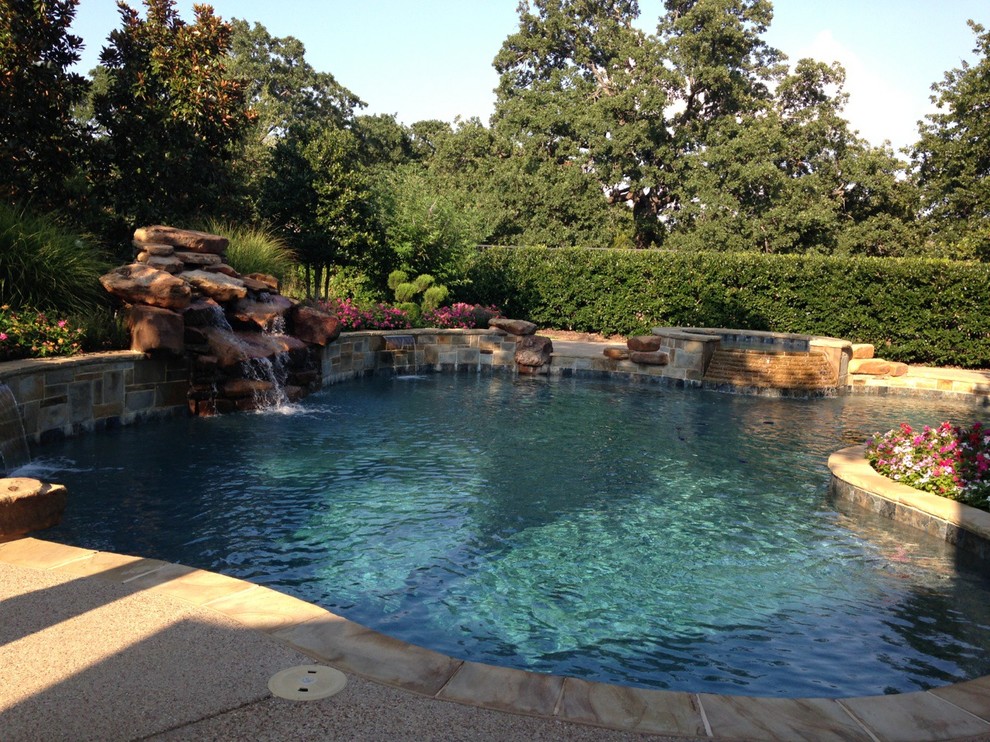 Inspiration for a large mediterranean backyard custom-shaped natural pool in Houston with a water feature and decking.