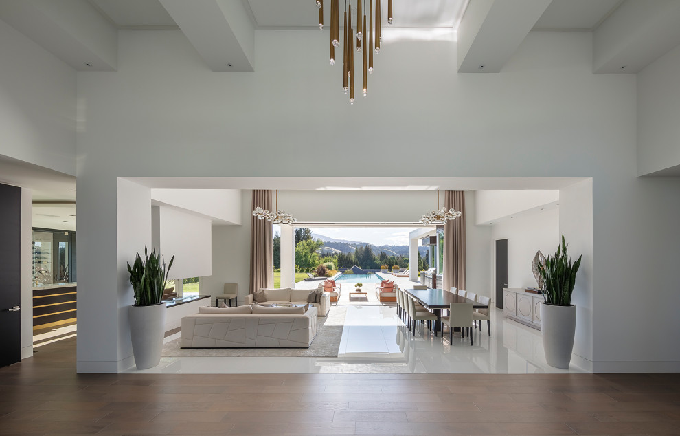 This is an example of an expansive modern open concept living room in San Francisco with white walls, marble floors, a concrete fireplace surround, white floor and coffered.