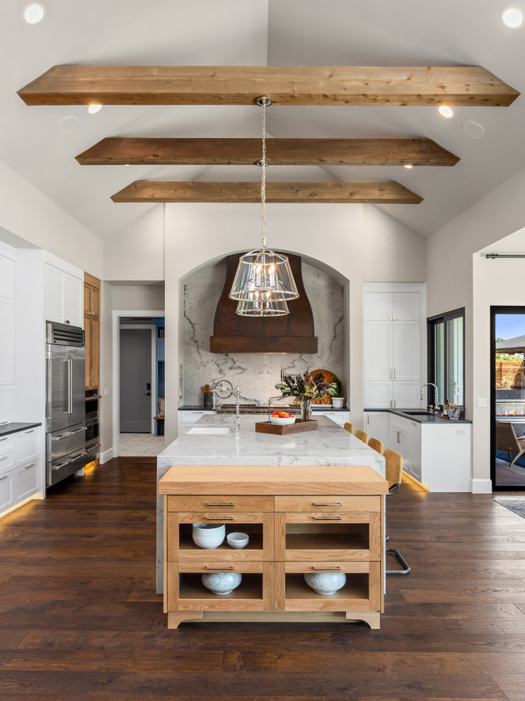 Inspiration for a large rural open plan kitchen in Portland with white cabinets, marble worktops, grey splashback, marble splashback, stainless steel appliances, dark hardwood flooring, an island, brown floors, grey worktops and exposed beams.