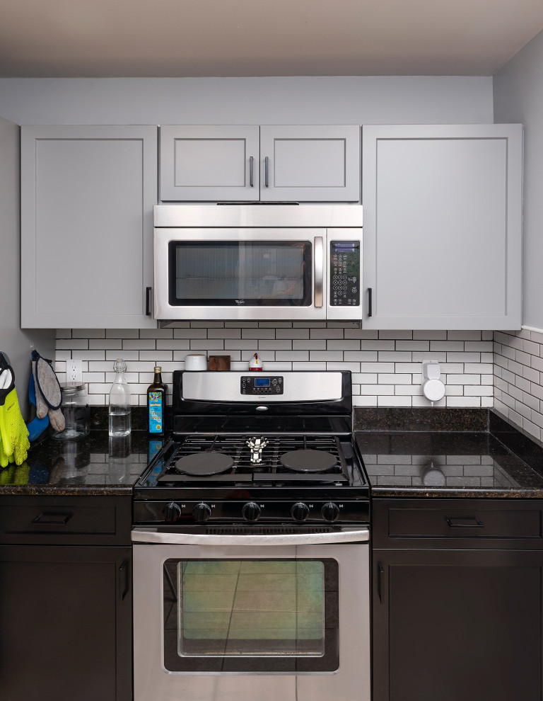 Design ideas for a small contemporary galley kitchen in Baltimore with an undermount sink, shaker cabinets, grey cabinets, granite benchtops, white splashback, subway tile splashback, stainless steel appliances, ceramic floors, multi-coloured floor and black benchtop.