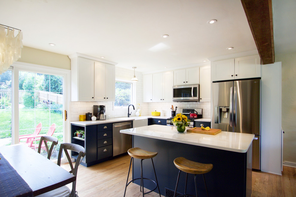 Eat-in kitchen - transitional medium tone wood floor eat-in kitchen idea with a farmhouse sink, shaker cabinets, blue cabinets, quartz countertops, white backsplash, subway tile backsplash, stainless steel appliances, an island and white countertops