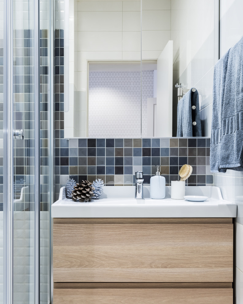 Inspiration for a mid-sized scandinavian 3/4 bathroom in Moscow with flat-panel cabinets, light wood cabinets, a corner shower, multi-coloured tile, blue tile, gray tile, ceramic tile, a sliding shower screen and an integrated sink.