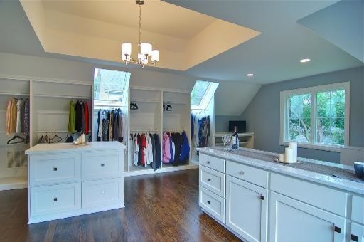 Inspiration for a large traditional gender-neutral walk-in wardrobe in Chicago with recessed-panel cabinets, white cabinets, medium hardwood floors, brown floor and recessed.