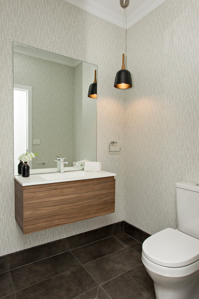 Photo of a small contemporary powder room in Sydney with flat-panel cabinets, medium wood cabinets, a one-piece toilet, mirror tile, grey walls, ceramic floors, a wall-mount sink, engineered quartz benchtops and black floor.