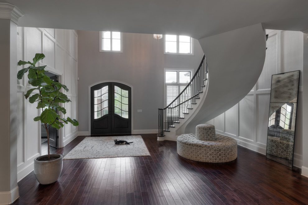 Large medium tone wood floor foyer photo with white walls and a black front door