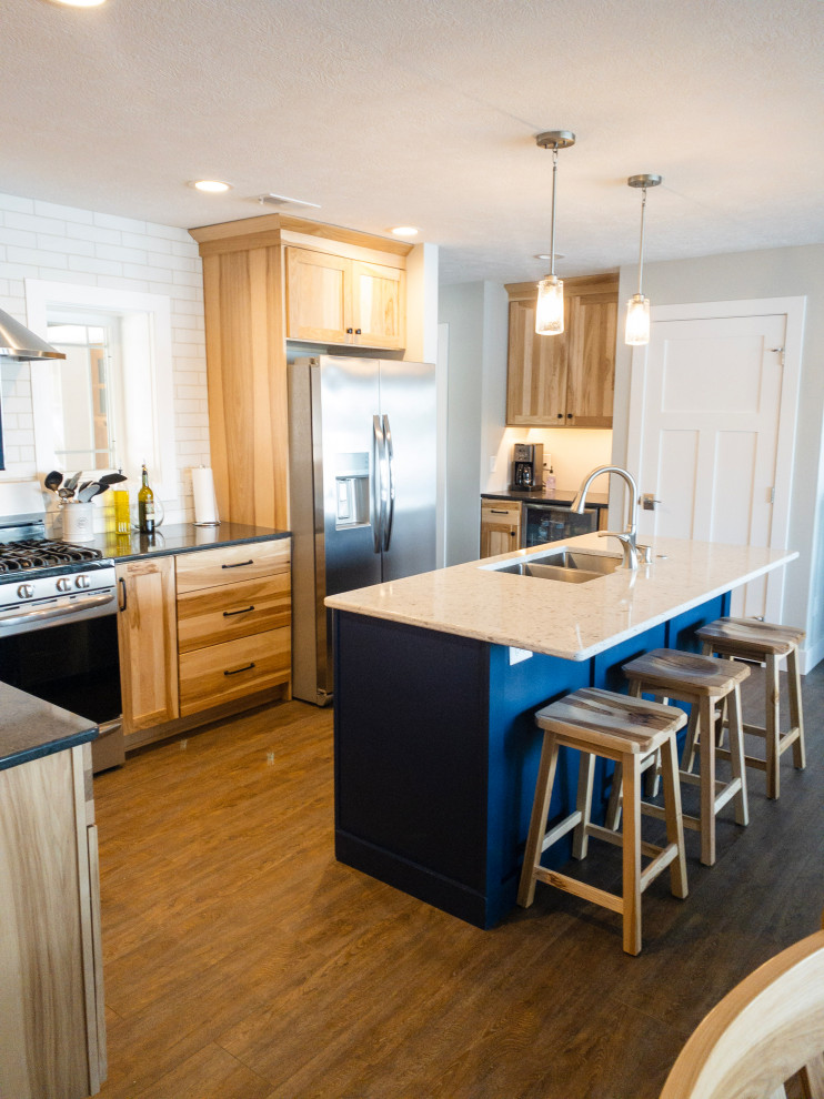 Mid-sized transitional l-shaped medium tone wood floor and brown floor eat-in kitchen photo with an undermount sink, flat-panel cabinets, light wood cabinets, quartz countertops, yellow backsplash, subway tile backsplash, stainless steel appliances, an island and white countertops