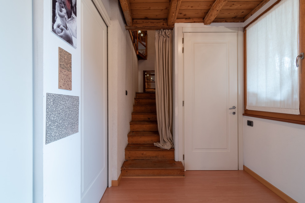Modelo de recibidores y pasillos rústicos de tamaño medio con paredes blancas, suelo de madera pintada, suelo naranja y vigas vistas