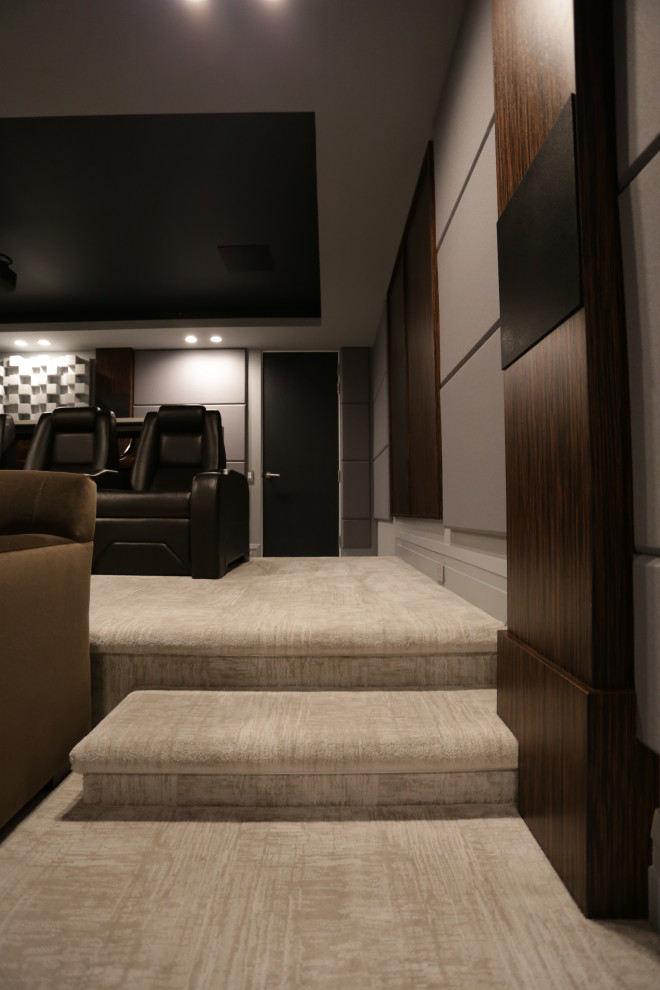 Стильный дизайн: большой изолированный домашний кинотеатр в современном стиле с серыми стенами, ковровым покрытием, проектором и бежевым полом - последний тренд