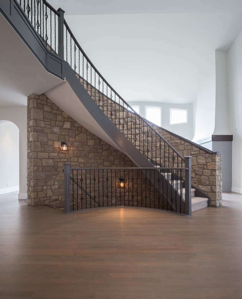 Photo of an expansive modern carpeted curved staircase in Calgary with carpet risers and wood railing.