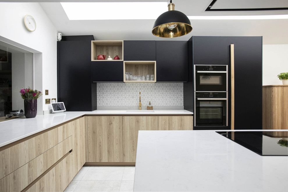 Small contemporary l-shaped open plan kitchen in London with a submerged sink, beaded cabinets, black cabinets, quartz worktops, white splashback, ceramic splashback, black appliances, ceramic flooring, an island, multi-coloured floors, white worktops, a vaulted ceiling and feature lighting.