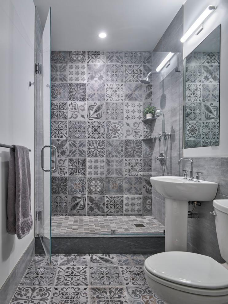 This is an example of a transitional 3/4 bathroom in New York with an alcove shower, a two-piece toilet, gray tile, cement tile, white walls, cement tiles, a pedestal sink, grey floor and a hinged shower door.
