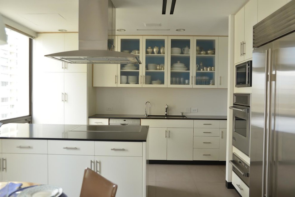 Large trendy l-shaped ceramic tile and brown floor eat-in kitchen photo in Orange County with white cabinets, stainless steel appliances, an island, granite countertops, a double-bowl sink and flat-panel cabinets