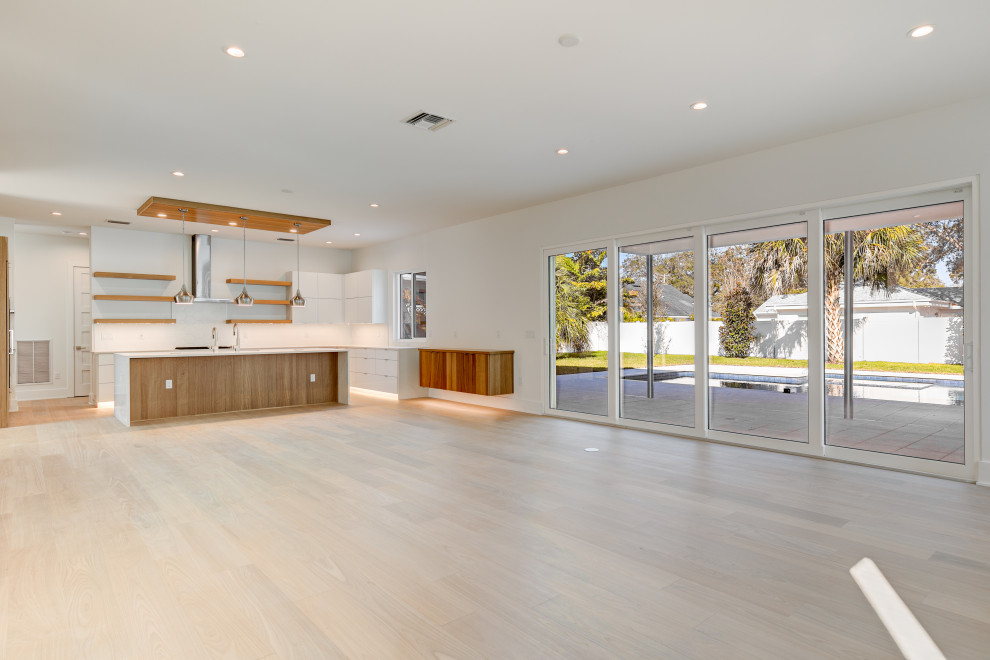 Foto de sala de estar abierta minimalista grande con paredes blancas, suelo de madera clara, chimenea lineal, televisor colgado en la pared y suelo beige