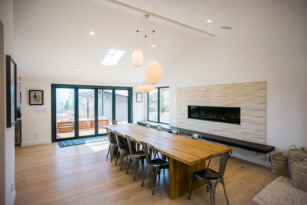 Large contemporary open plan dining in San Francisco with white walls, light hardwood floors, a ribbon fireplace and a tile fireplace surround.
