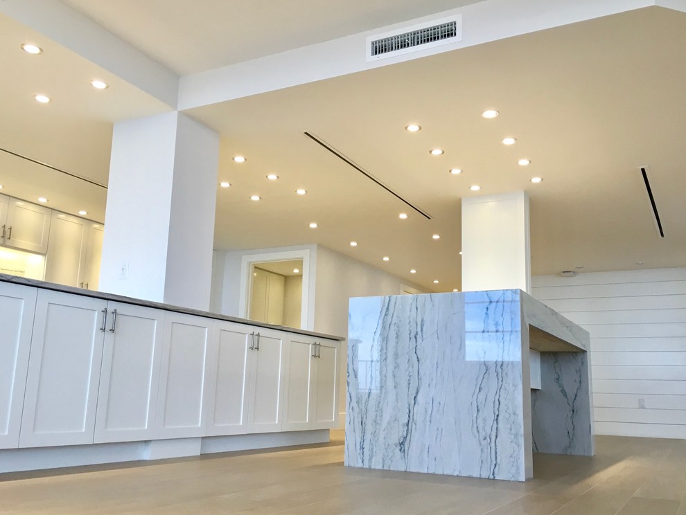 Inspiration for a large transitional galley light wood floor and beige floor open concept kitchen remodel in Miami with an undermount sink, shaker cabinets, white cabinets, marble countertops, gray backsplash, marble backsplash, stainless steel appliances and an island
