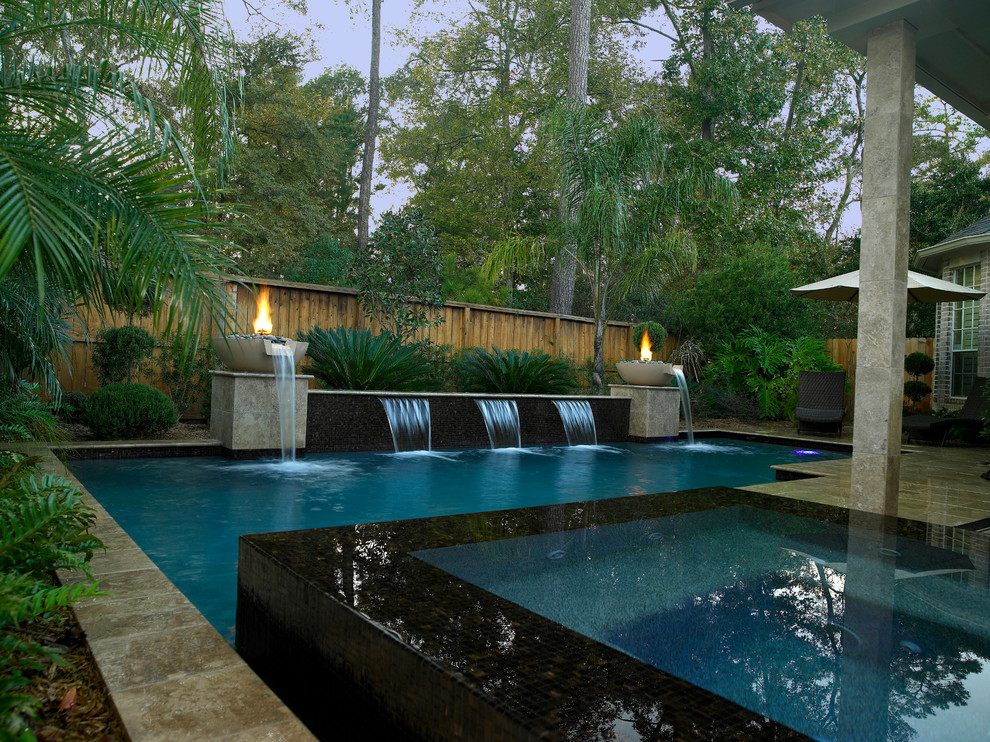 Photo of a large contemporary backyard l-shaped lap pool in Houston with a water feature and tile.