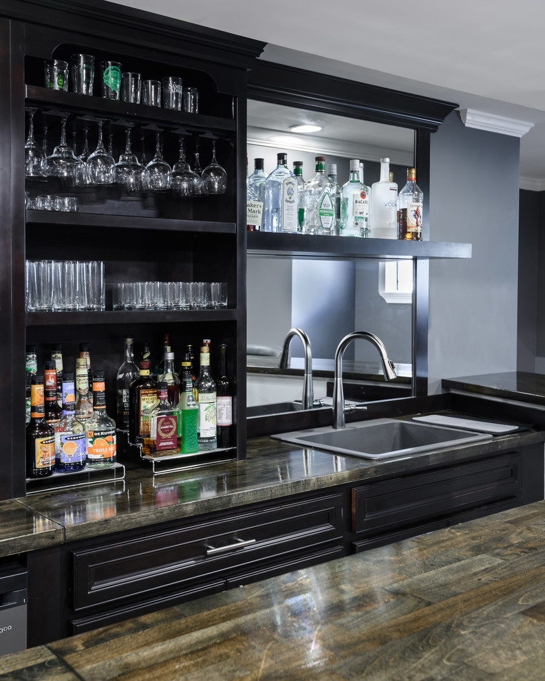 Photo of a mid-sized modern single-wall seated home bar in St Louis with a drop-in sink, open cabinets, black cabinets, wood benchtops, mirror splashback, carpet, beige floor and brown benchtop.