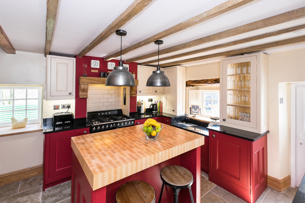 Medium sized rustic enclosed kitchen in Other with a belfast sink, shaker cabinets, red cabinets, granite worktops, black appliances, limestone flooring and an island.