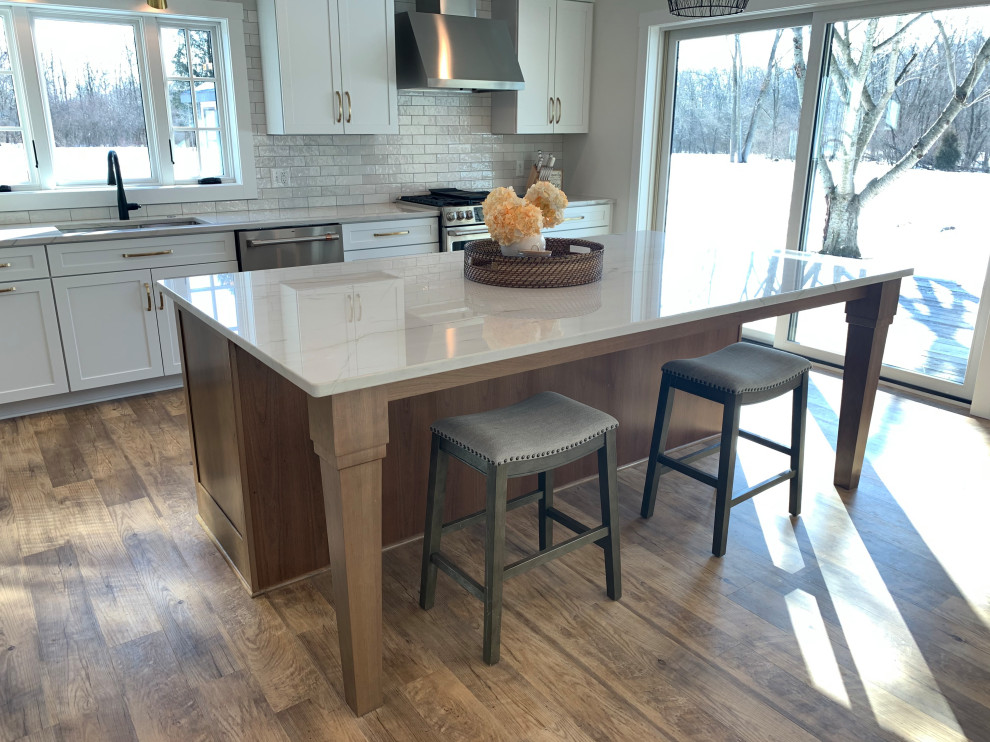 Inspiration for a large transitional l-shaped vinyl floor and brown floor eat-in kitchen remodel with an undermount sink, shaker cabinets, white cabinets, quartz countertops, stainless steel appliances, an island and gray countertops