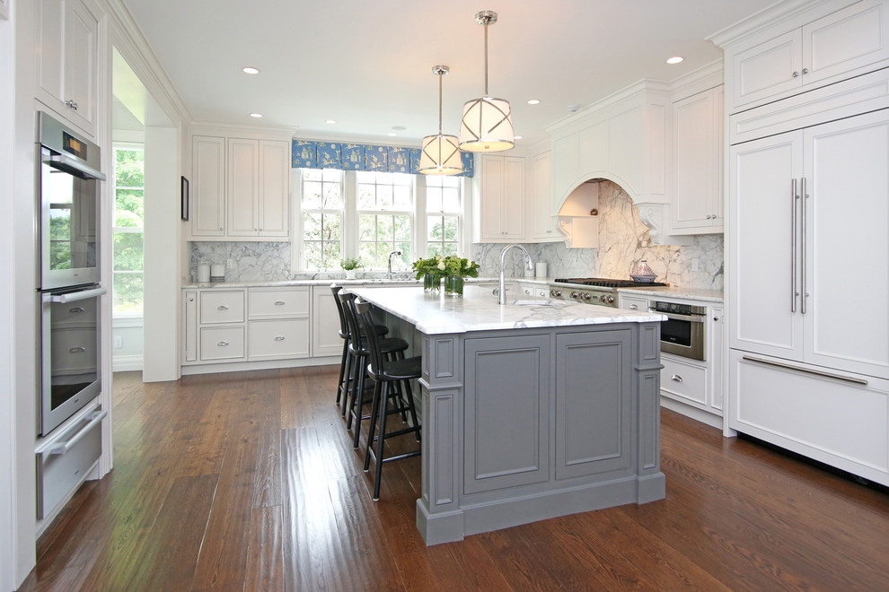 This is an example of a traditional u-shaped separate kitchen in Boston with recessed-panel cabinets, white cabinets, white splashback, stainless steel appliances, dark hardwood floors, with island, marble benchtops and cement tile splashback.