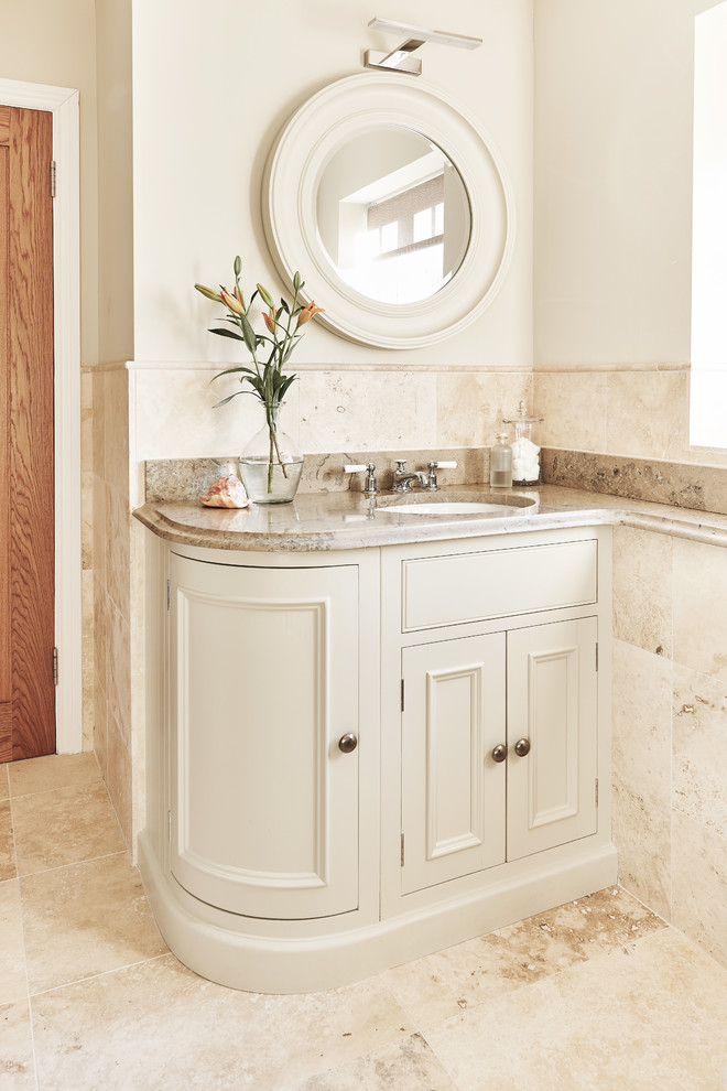 Small traditional bathroom in Berkshire with white cabinets, beige tile, stone tile, white walls, travertine floors, an undermount sink, limestone benchtops and recessed-panel cabinets.