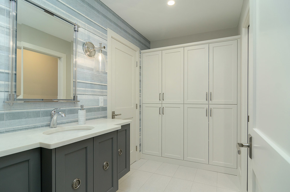 This is an example of a small beach style bathroom in Minneapolis with furniture-like cabinets, a corner tub, a corner shower, a wall-mount toilet, beige tile, porcelain tile, grey walls, laminate floors, an undermount sink, solid surface benchtops, brown floor, a shower curtain and beige benchtops.