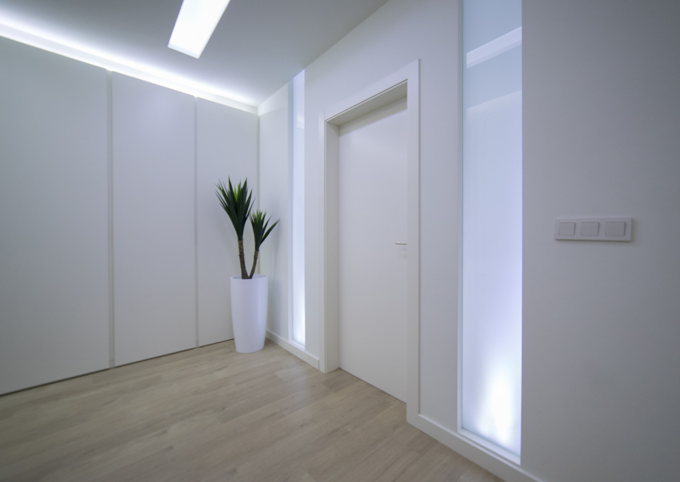 This is an example of a contemporary hallway in Valencia with white walls, medium hardwood floors and brown floor.
