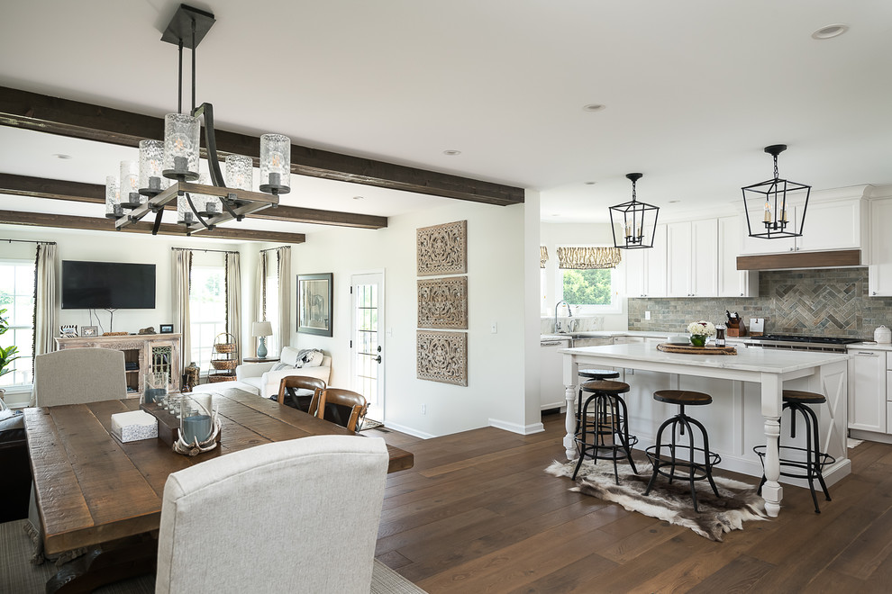 Photo of a large country l-shaped open plan kitchen in Other with a farmhouse sink, recessed-panel cabinets, white cabinets, marble benchtops, multi-coloured splashback, porcelain splashback, stainless steel appliances, medium hardwood floors, with island, brown floor and white benchtop.