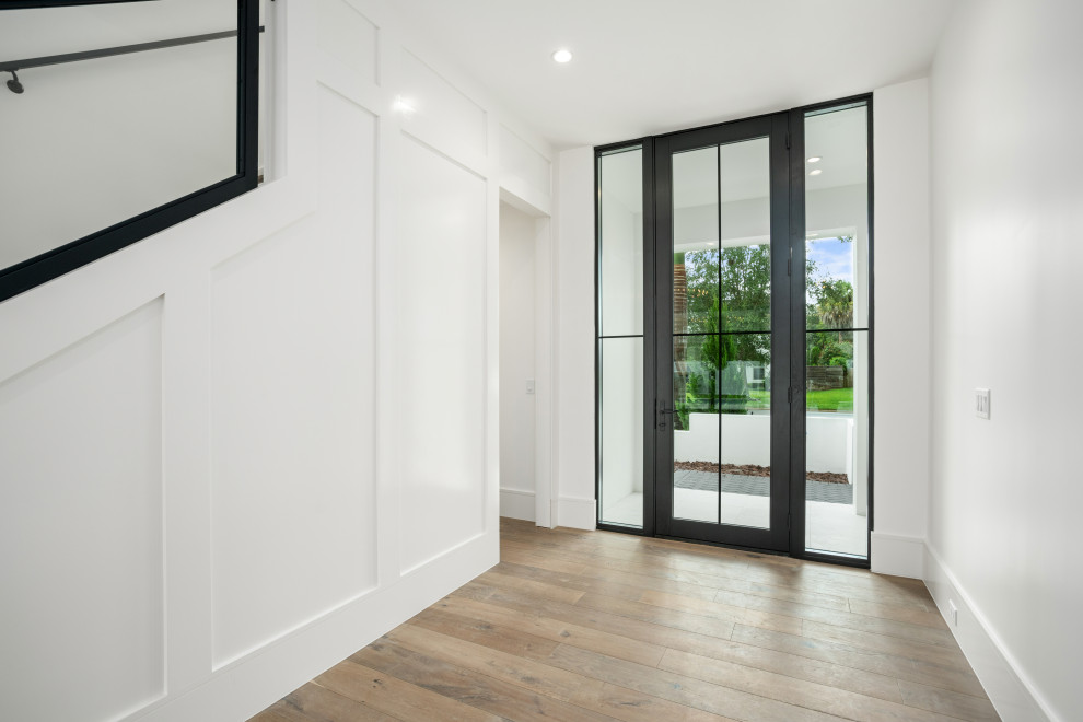 Example of a transitional medium tone wood floor foyer design in Orlando with white walls