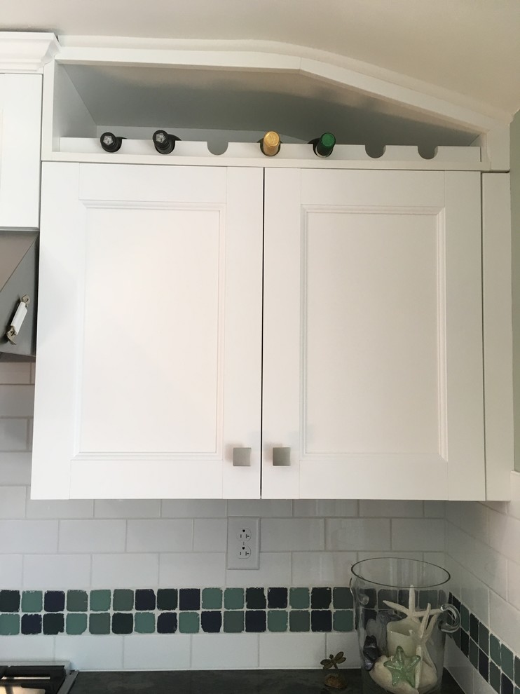 Enclosed kitchen - mid-sized transitional l-shaped light wood floor enclosed kitchen idea with an undermount sink, flat-panel cabinets, white cabinets, granite countertops, white backsplash, subway tile backsplash, stainless steel appliances and no island