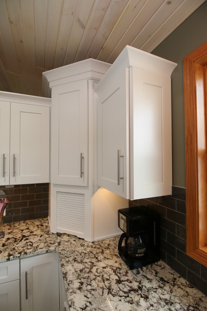 This is an example of a large traditional l-shaped eat-in kitchen in Cleveland with a double-bowl sink, shaker cabinets, white cabinets, granite benchtops, grey splashback, subway tile splashback, stainless steel appliances, medium hardwood floors and with island.