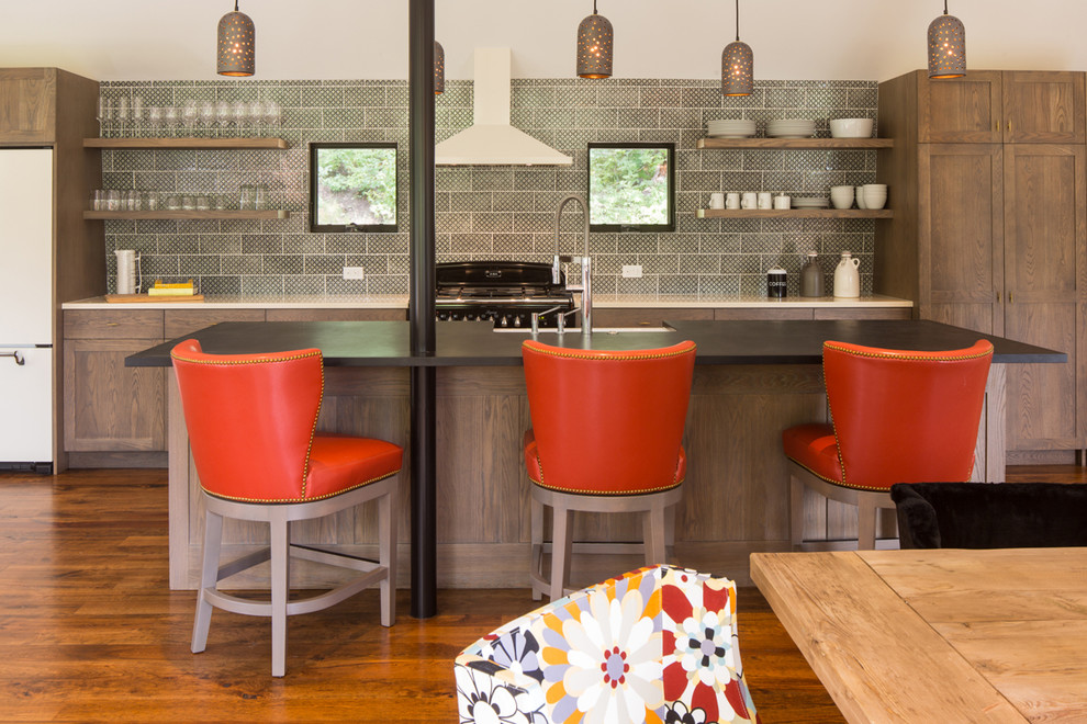 Example of a large mountain style galley medium tone wood floor eat-in kitchen design with a farmhouse sink, open cabinets, dark wood cabinets, solid surface countertops, multicolored backsplash, ceramic backsplash and an island