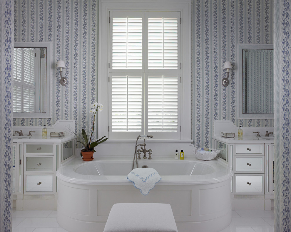 This is an example of a beach style master bathroom in Miami with white cabinets, an undermount tub, multi-coloured walls and recessed-panel cabinets.