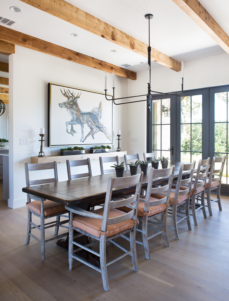 Photo of a country dining room in Austin with white walls and light hardwood floors.