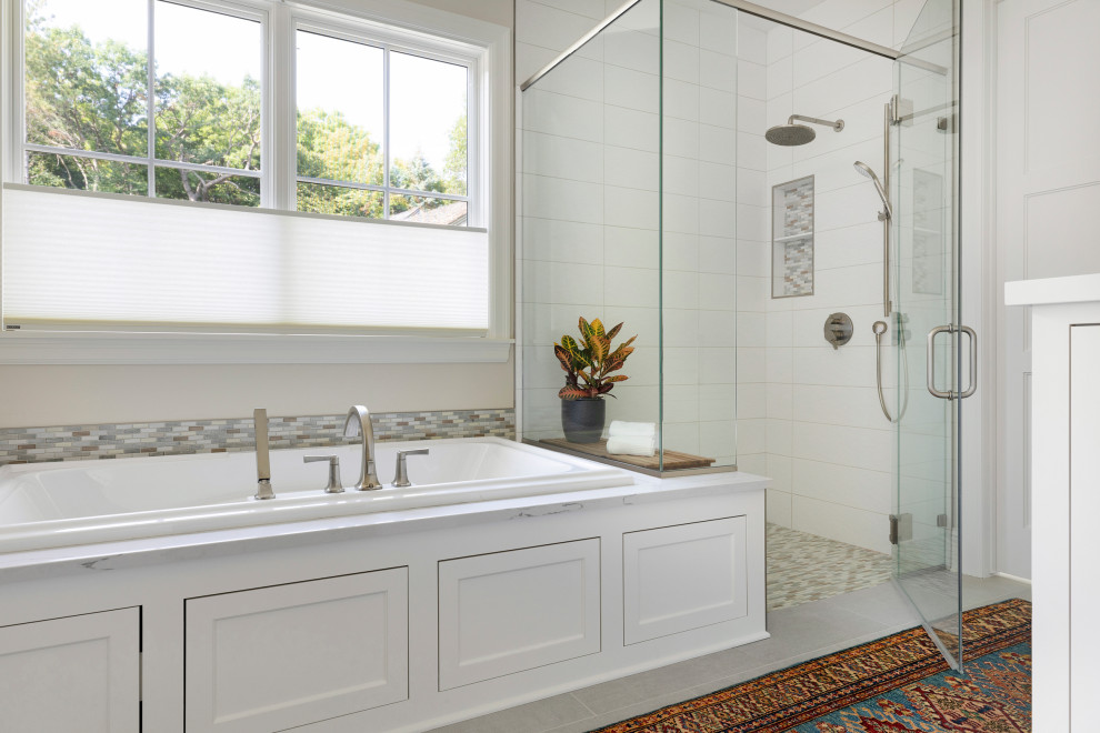 Large traditional master bathroom in Minneapolis with recessed-panel cabinets, white cabinets, a drop-in tub, a curbless shower, a one-piece toilet, white tile, porcelain tile, beige walls, porcelain floors, a wall-mount sink, engineered quartz benchtops, grey floor, a hinged shower door and grey benchtops.