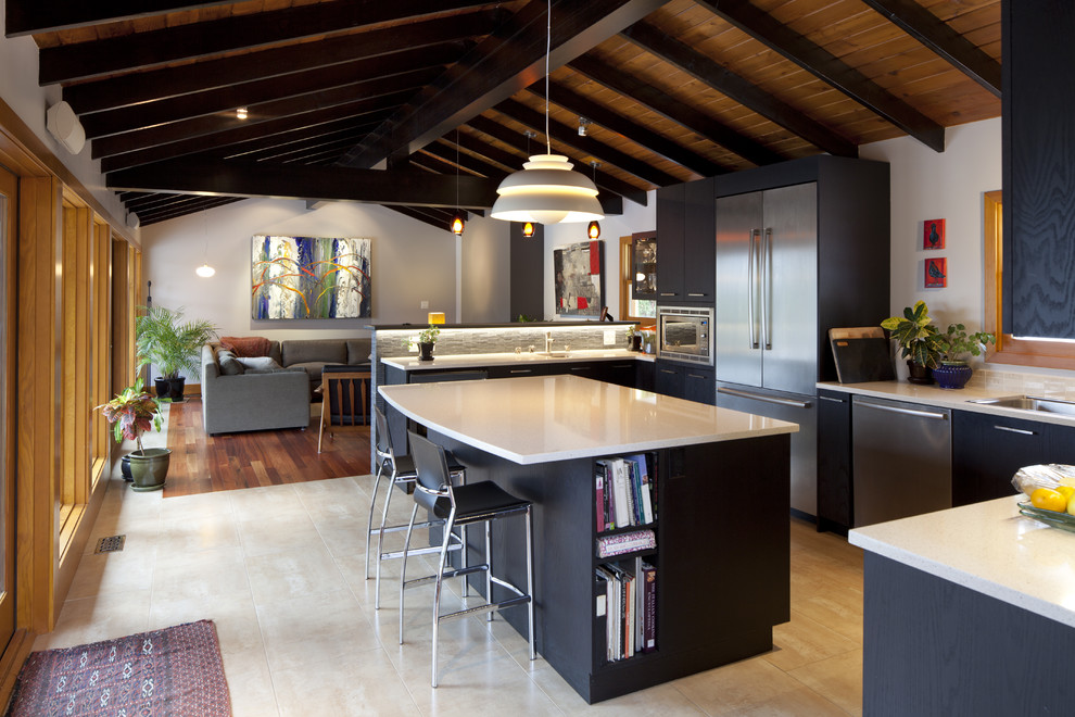 Photo of a country u-shaped open plan kitchen in Vancouver with a drop-in sink, black cabinets, flat-panel cabinets and stainless steel appliances.