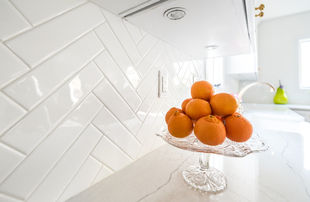 Example of a transitional medium tone wood floor kitchen design in Richmond with a farmhouse sink, shaker cabinets, white cabinets, quartzite countertops, white backsplash, subway tile backsplash, stainless steel appliances and an island