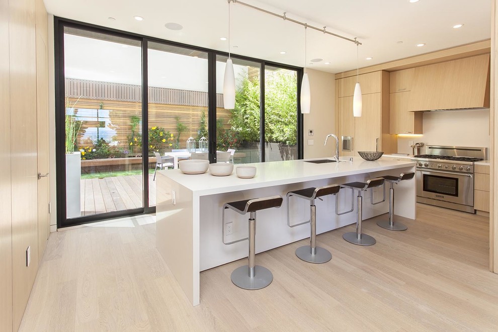 This is an example of a mid-sized contemporary l-shaped kitchen in San Francisco with an undermount sink, flat-panel cabinets, light wood cabinets, stainless steel appliances, light hardwood floors and with island.
