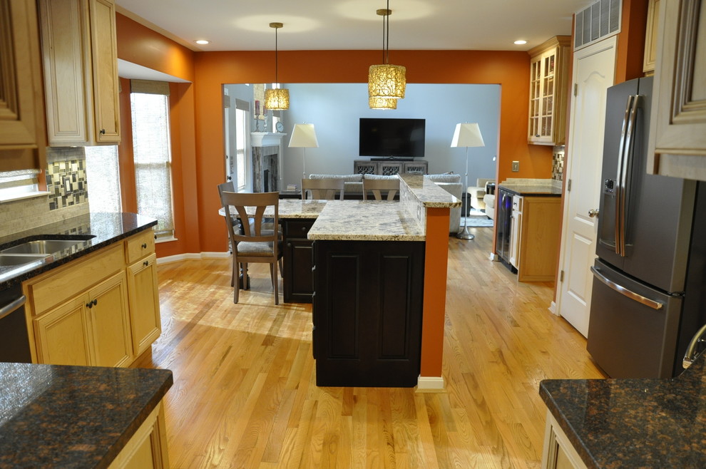 Example of a mid-sized transitional u-shaped light wood floor eat-in kitchen design in Cincinnati with an undermount sink, raised-panel cabinets, light wood cabinets, granite countertops, gray backsplash, glass sheet backsplash, colored appliances and an island
