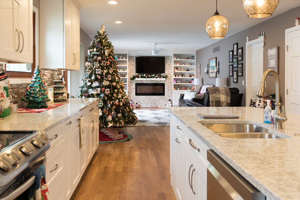 This is an example of a large modern kitchen in Cincinnati with an undermount sink, shaker cabinets, white cabinets, quartz benchtops, multi-coloured splashback, glass tile splashback, stainless steel appliances, medium hardwood floors, with island and brown floor.