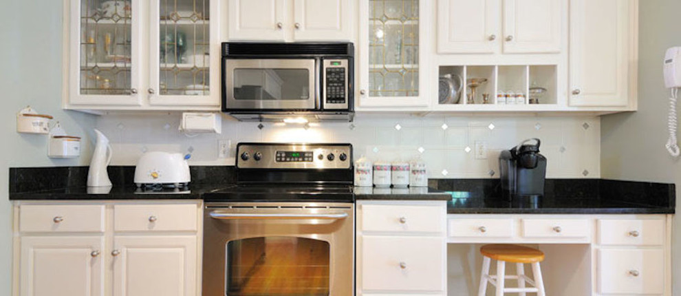 Mid-sized kitchen photo with flat-panel cabinets, white cabinets, white backsplash, ceramic backsplash and stainless steel appliances