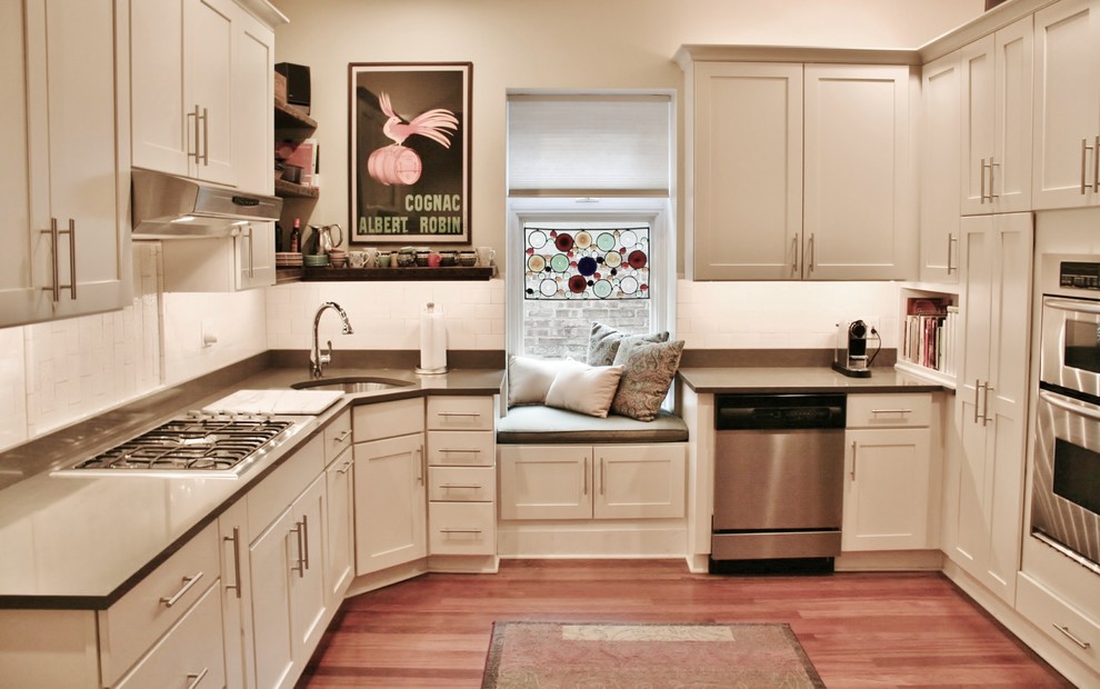 Large transitional u-shaped light wood floor and brown floor enclosed kitchen photo in Chicago with an undermount sink, shaker cabinets, white cabinets, quartz countertops, white backsplash, subway tile backsplash, stainless steel appliances and no island