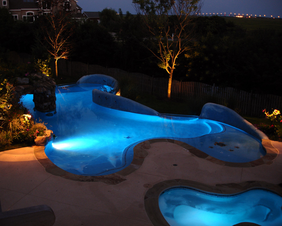 Inspiration for a large tropical backyard custom-shaped lap pool in New York with a water feature and concrete slab.