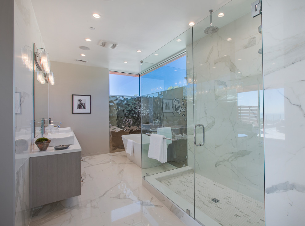 Mid-sized contemporary master bathroom in Los Angeles with flat-panel cabinets, medium wood cabinets, a freestanding tub, a corner shower, a one-piece toilet, white tile, porcelain tile, beige walls, porcelain floors, a vessel sink, solid surface benchtops, white floor, a hinged shower door and white benchtops.