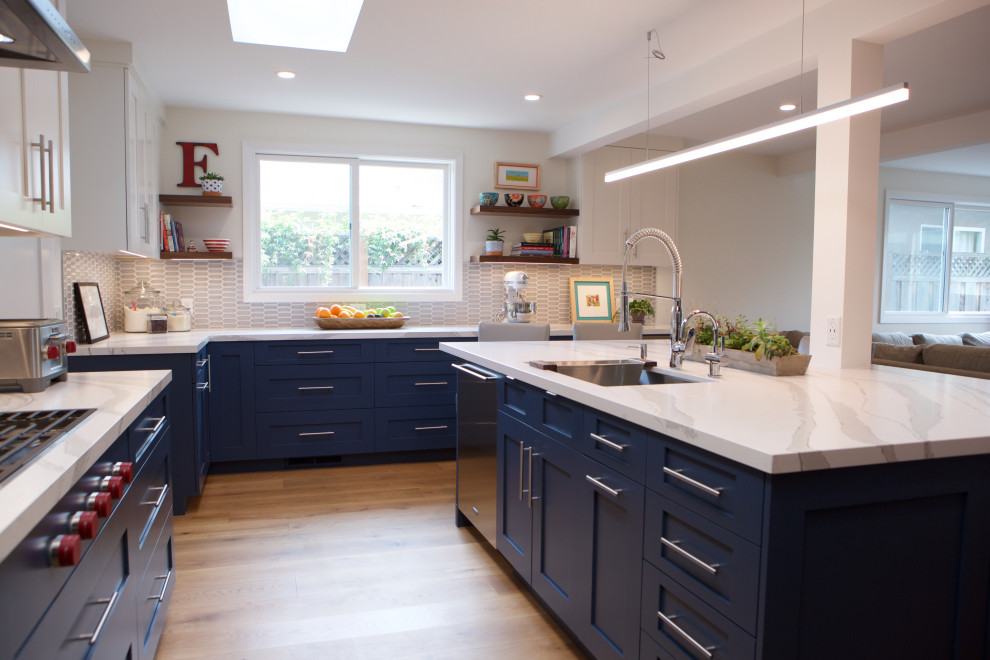Large transitional u-shaped medium tone wood floor open concept kitchen photo in San Francisco with a single-bowl sink, recessed-panel cabinets, blue cabinets, quartz countertops, gray backsplash, mosaic tile backsplash, stainless steel appliances, an island and white countertops