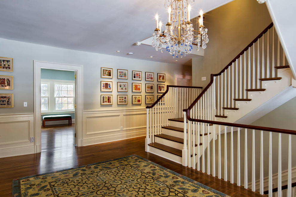 This is an example of an expansive traditional wood u-shaped staircase in New York with wood risers and wood railing.