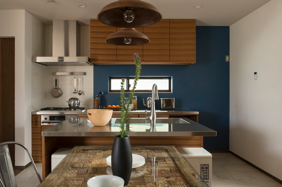 This is an example of a midcentury galley kitchen in Other with an integrated sink, flat-panel cabinets, medium wood cabinets, stainless steel benchtops, with island, beige floor and brown benchtop.