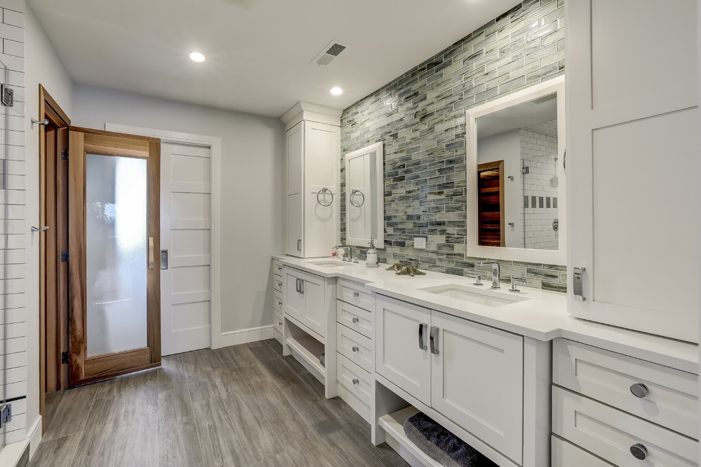 Inspiration for a bathroom in New York with furniture-like cabinets, a two-piece toilet, gray tile, grey walls, porcelain floors, an undermount sink, engineered quartz benchtops, grey floor, an alcove shower, glass sheet wall, a hinged shower door and white cabinets.